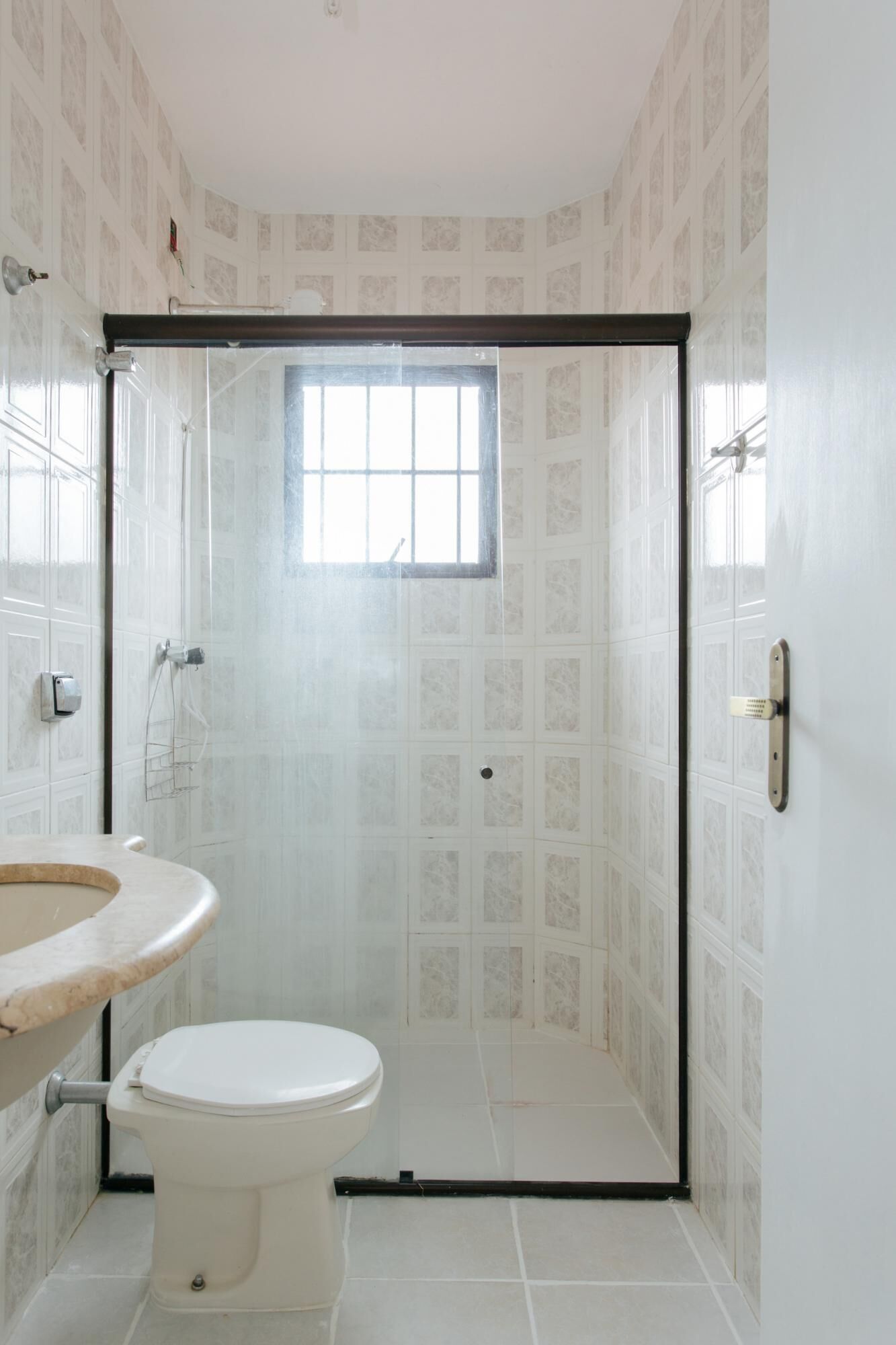 A bathroom with a toilet, a sink, and a shower enclosure with a window.