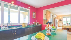 A kitchen with a green countertop, a sink, and a window. There are bananas and a bowl on the countertop. - Villa Triantafyllo in Kentroma (Corfu)