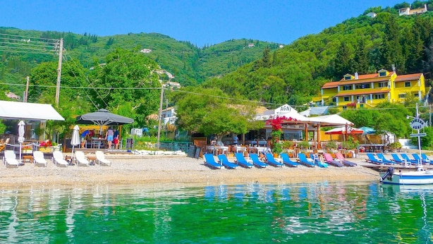 A coastal area with a beach, lounge chairs, and a boat. - Villa Triantafyllo in Kentroma (Corfu)