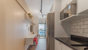 A modern kitchen with white cabinetry, a stainless steel refrigerator, and a black countertop. - Rep1203 Setin Downtown Rep Blica (São Paulo)