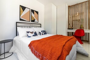 A modern bedroom with a bed, a red chair, and abstract wall art. - Av0102 Studio Avanhandava (São Paulo)
