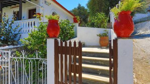 A house with a white exterior, a red roof, and a gated entrance.