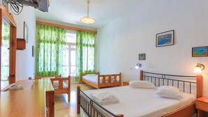 A room with two single beds, a wooden desk, a table, and a chair.
