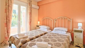 Une chambre avec deux lits, un balcon et un lustre.