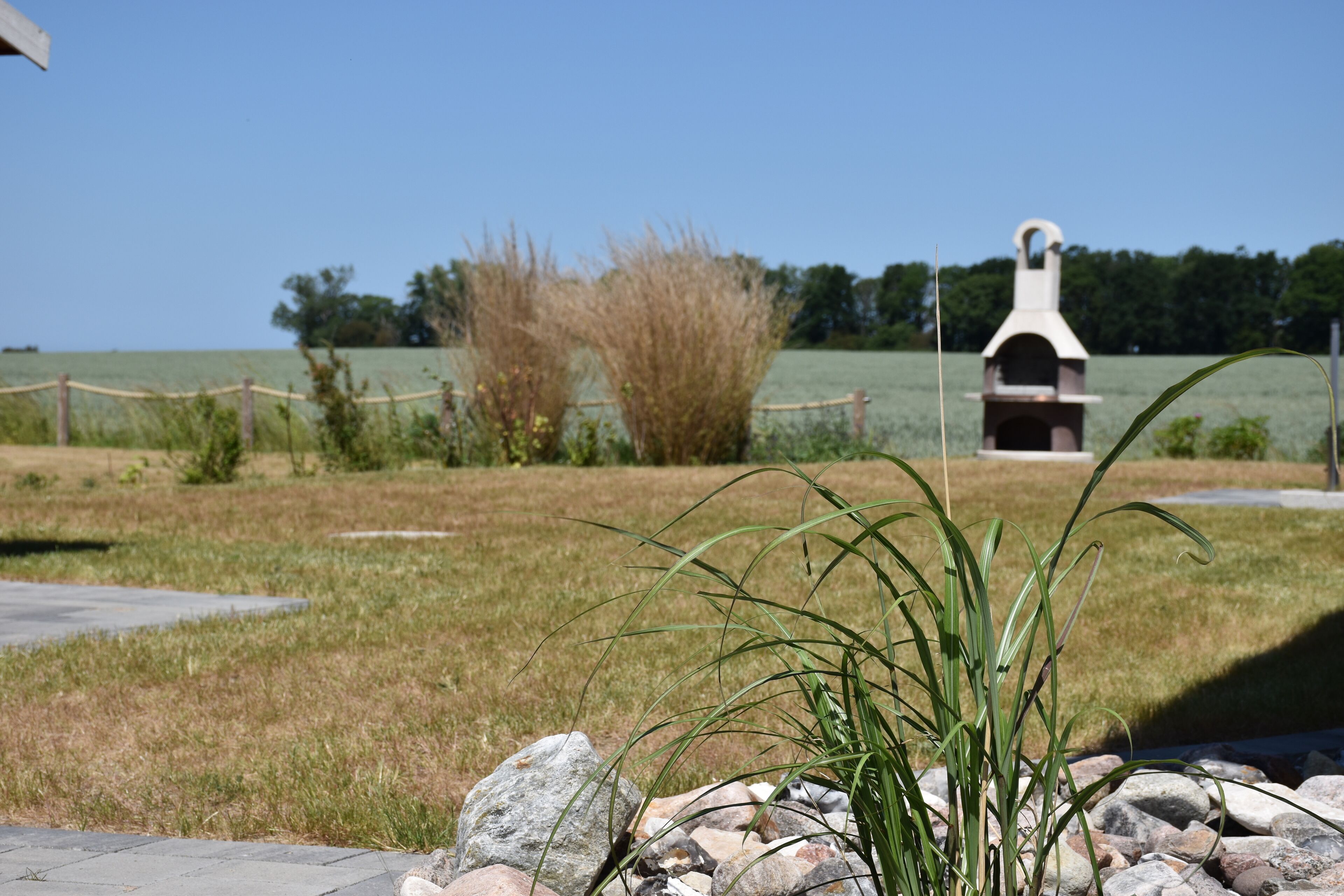 A grassy area with a barbecue grill and a rope barrier.