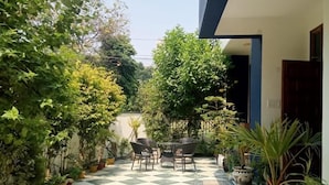 Un patio con suelo a cuadros, plantas en macetas y mobiliario exterior.
