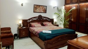 Un dormitorio con cama de madera, mesitas de noche, una silla, un armario y un cuadro en la pared.