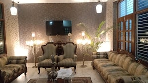 Una sala de estar tradicional con un conjunto de sofás, una mesa de centro y un televisor montado en la pared.