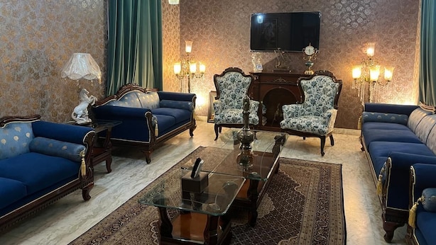Una sala de estar tradicional con chimenea, dos sofás, dos sillones, una mesa de centro y un televisor de pantalla plana montado en la pared.