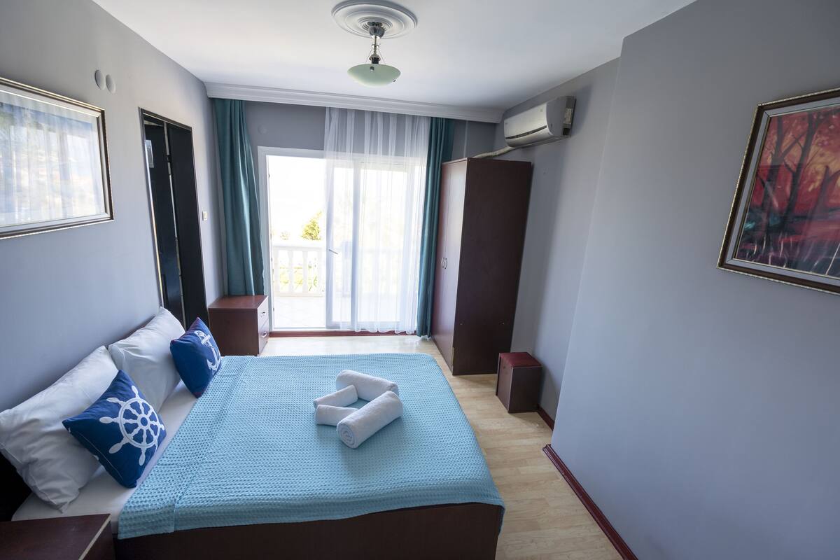 Quarto de hotel com cama, guarda-roupa, janela com cortinas e ar condicionado.