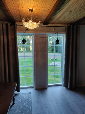 Ein Zimmer mit Holzbalkendecke, einem Chandelier und großen Fenstern mit Vorhängen.