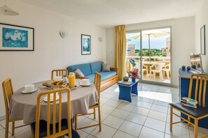 Un comedor con una mesa lista para dos personas, un sofá y un balcón con vistas.