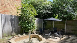 A backyard with a stone fire pit, a wooden fence, and outdoor furniture.