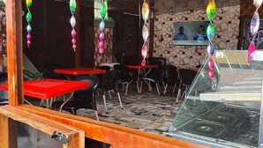 A restaurant with a wooden exterior, red tables, and hanging decorative elements. - Oak Valley Hotel & Event Center (Port Harcourt)
