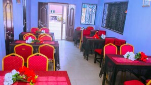 A dining area with red and yellow chairs, tables with red tablecloths, and floral centerpieces. - Oak Valley Hotel & Event Center (Port Harcourt)