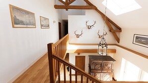 A wooden staircase with a chandelier, a wooden cabinet, and wall-mounted deer antlers. - Spacious house, private pool, 10 to 15 p. (Chémery)