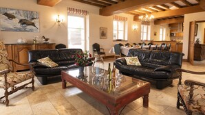 A spacious living room with leather sofas, a wooden coffee table, and a dining area with a kitchen in the background. - Spacious house, private pool, 10 to 15 p. (Chémery)
