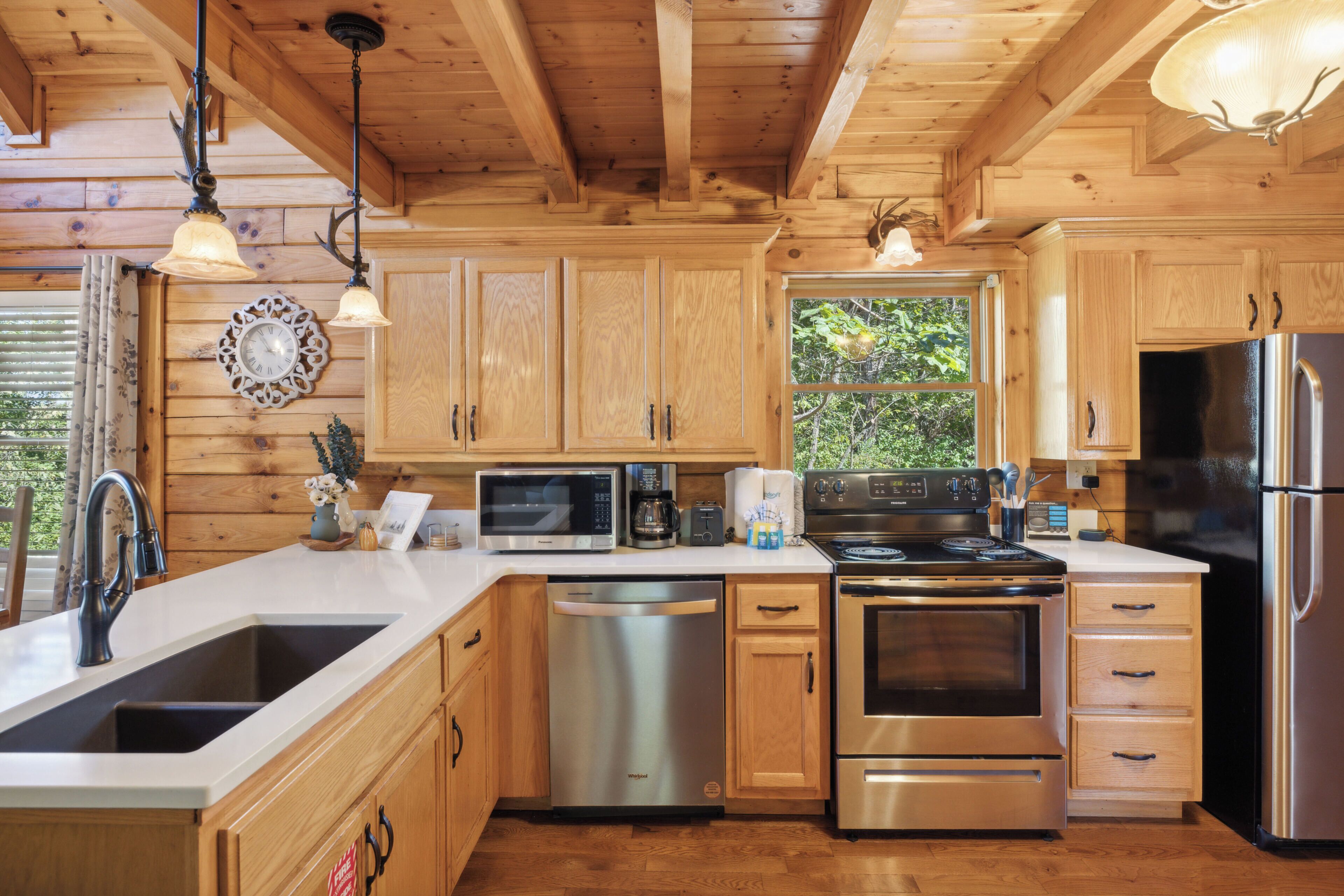 Cocina de cabaña de madera con lavamanos, estufa, refrigerador y armarios de madera.