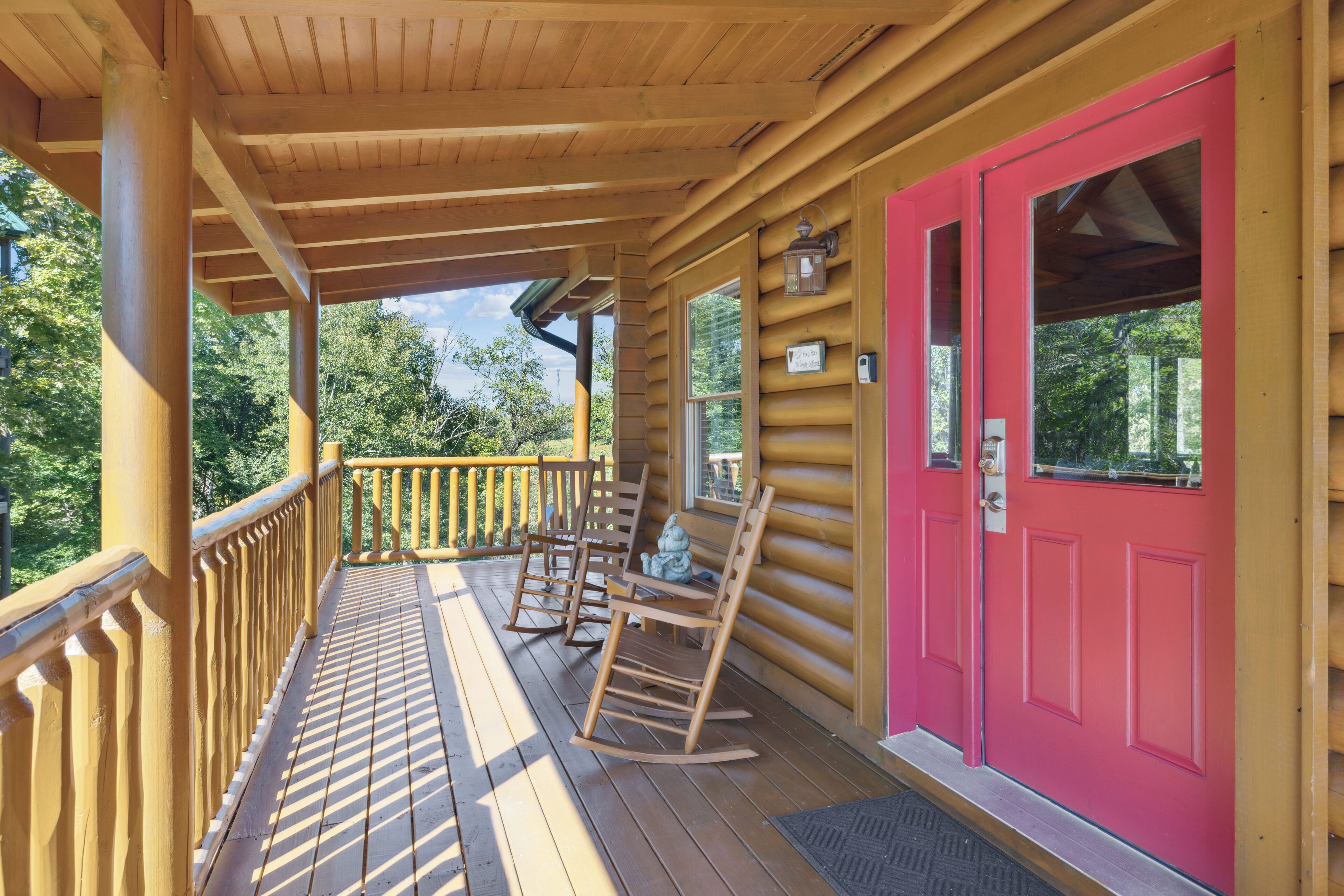 A wooden porch with rocking chairs and a bright pink door.
