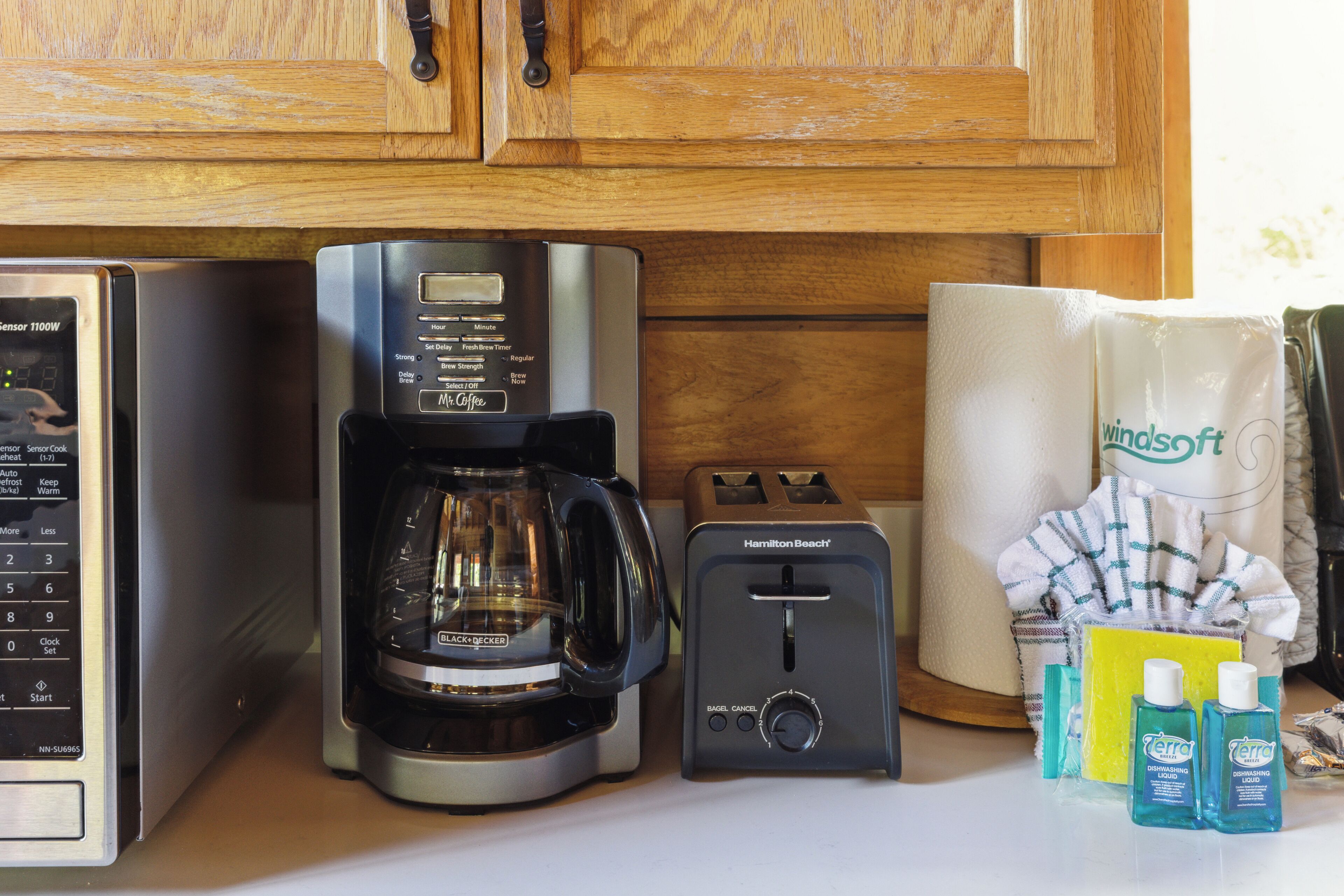 A kitchen with a coffee maker, toaster, and cleaning supplies.