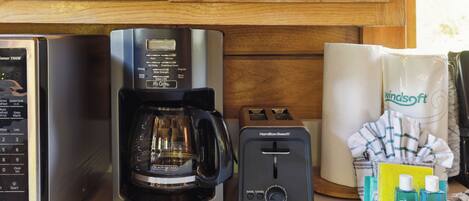 A kitchen with a coffee maker, toaster, and cleaning supplies.