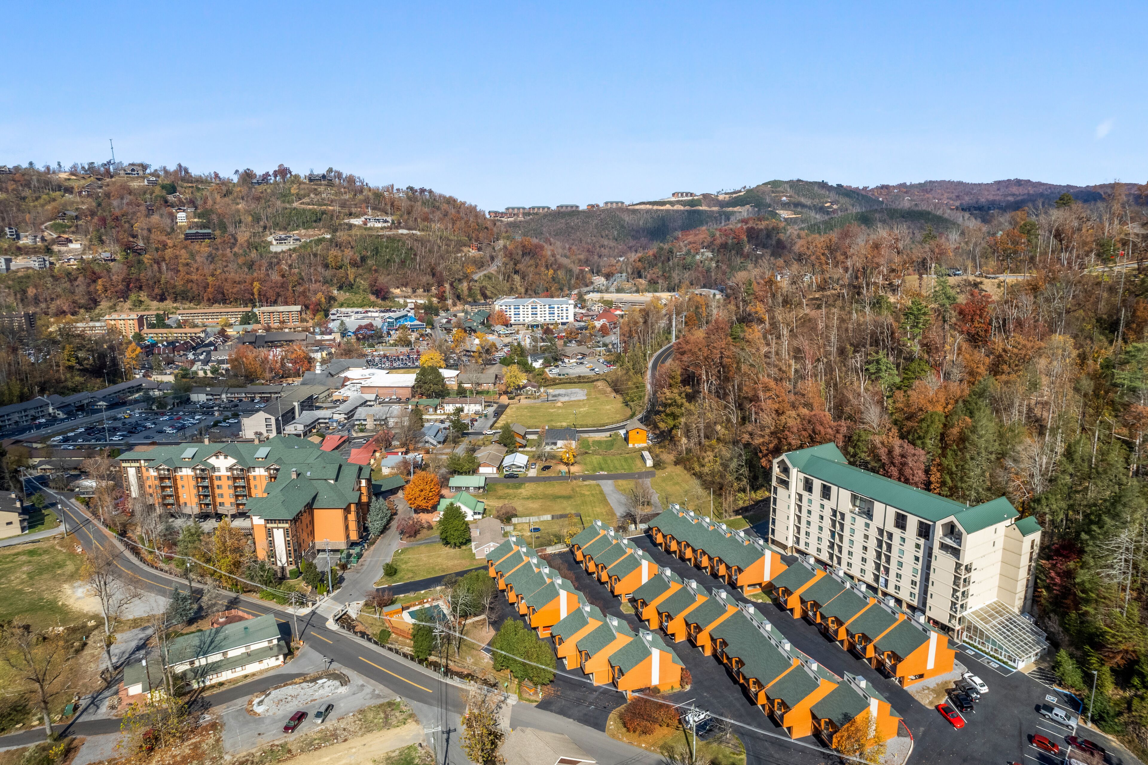A hotel with multiple buildings, a parking lot, and surrounding hills.