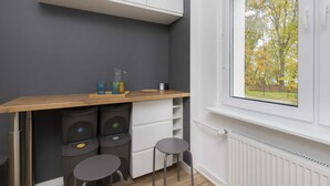 A compact kitchen with a wooden countertop, white cabinets, and a window with a view of trees.
