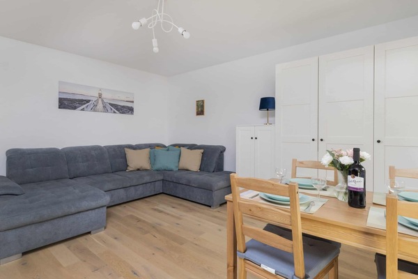 Another view of the living room showcasing the gray sofa and the dining area.