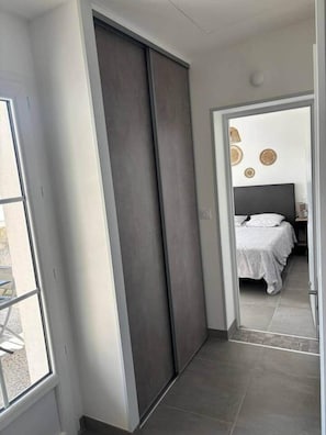 Un dormitorio moderno con una cama grande, una puerta corredera oscura y vistas al exterior a través de una ventana.