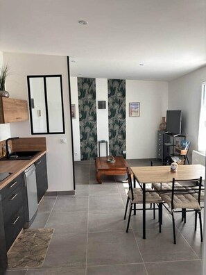 A modern kitchen with dark cabinetry, a wooden countertop, and a built-in dishwasher.