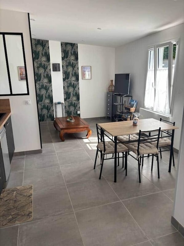 Eine moderne Küche mit dunklen Schränken, einem Holzespeisetisch mit Stühlen und einem Fernseher auf einem Lowboard.