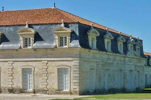 A large, historic building with a symmetrical facade, multiple arched windows, and a tiled roof.