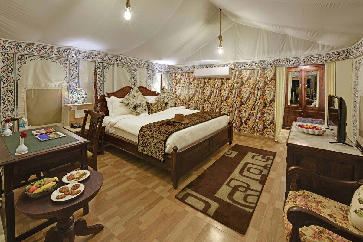 A spacious room with a large bed, a wooden desk, and a dining table with plates of food.