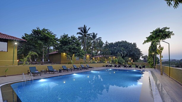 A swimming pool with lounge chairs and a view of the surrounding greenery. -  GIR LION SAFARI CAMP (Mendarda)