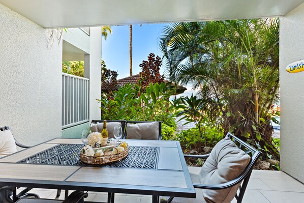Un patio con una mesa dispuesta para dos personas, rodeado de exuberante vegetación y una vista despejada del cielo.