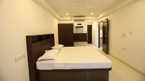 A bedroom with a large bed, a ceiling fan, an air conditioning unit, and a wardrobe. - Hotel Rydham (Madurai)