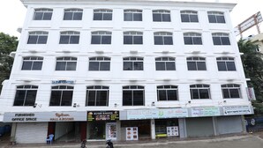A multi-story building with various businesses on the ground floor, including a health center, cafe, and office space. - Hotel Rydham (Madurai)