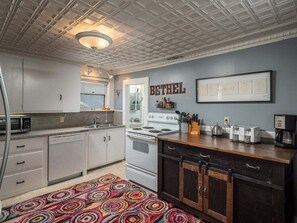 Una cocina con armarios blancos, estufa, microondas y cafetera.