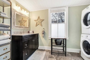 A laundry room with a washing machine, a sink, a mirror with star decorations, and a window. - Bethel Village Retreat (Bethel)