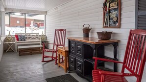 Une pièce chaleureuse avec un banc en bois, des chaises rouges, une petite table avec une bouilloire et un panneau fixé au mur.