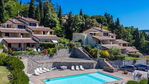 Zona residencial con piscina rodeada de sillas de descanso y un muro de piedra.