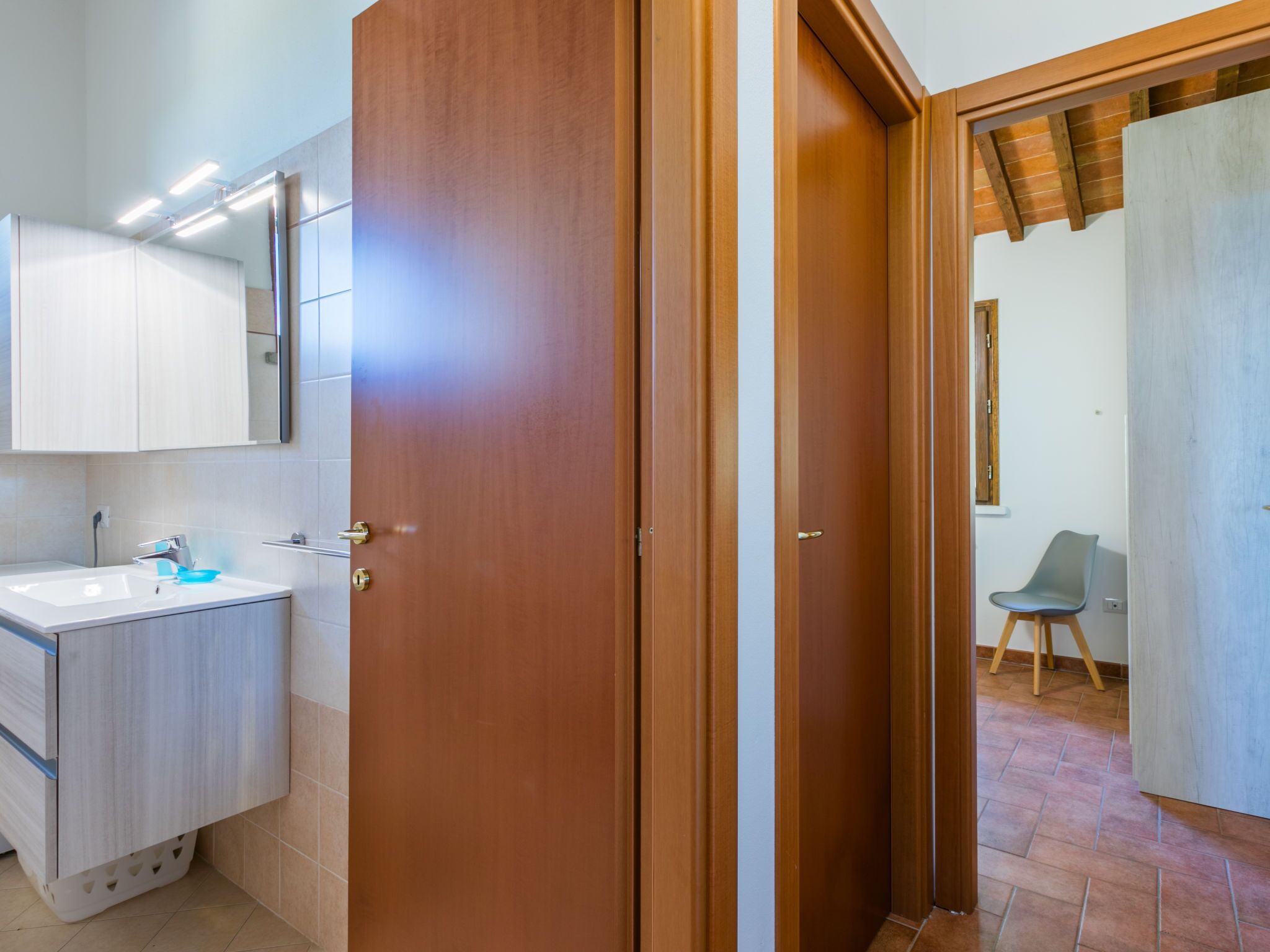 A bathroom with a wooden door, a white sink, and a mirror.