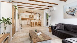 Una sala de estar moderna con una mesa de centro de madera, un sofá de cuero negro y una zona de cocina con un taburete de bar.