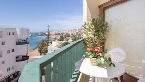 Un balcon avec vue sur la mer, une table avec un panier de fleurs et une chaise.