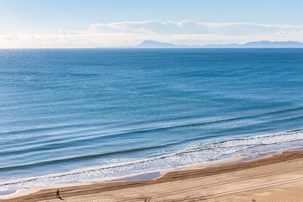 Una playa con vista despejada al océano y montañas a lo lejos.