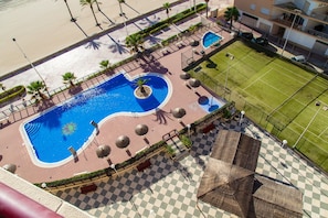 Oversigtsbillede af et resort med en central swimmingpool, en tennisbane og et skakternet pladse.