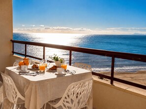 En balkon med et morgenbord, udsigt over havet.