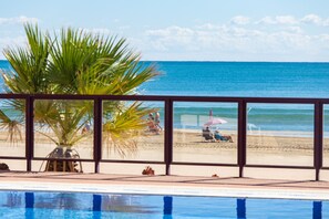 A pool area with a view of the beach and ocean.