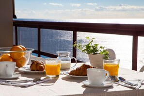 Una mesa de desayuno con cruasanes, jugo de naranja y un bol de naranjas.