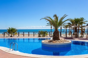 A pool with a clear view of the beach and ocean.